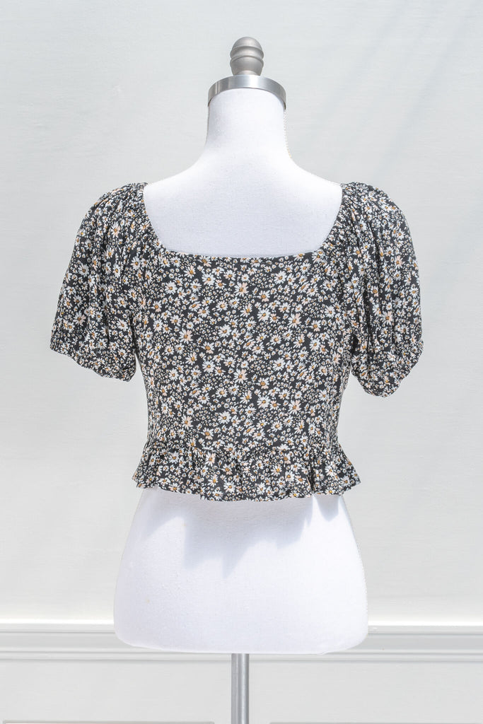 feminine tops - a white daisy small print on black background blouse, with tie front, buttons, and short sleeves - feminine style from amantine - back view 