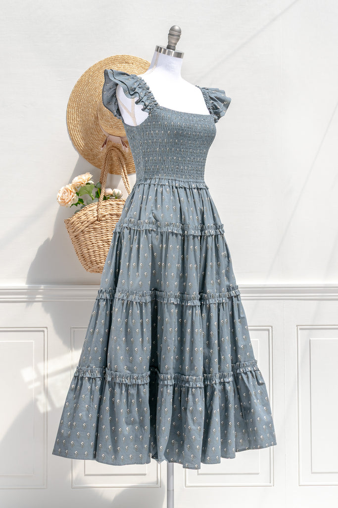 Camille dusty blue floral smocked midi dress — three-quarter view showing ruffled sleeves and tiered silhouette 2