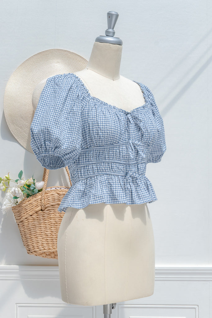 feminine clothing - a white and blue gingham peplum top with a sweetheart neckline and puff sleeves. perfect for summer activities or to feel romantic. 3/4 side view. amantine.
