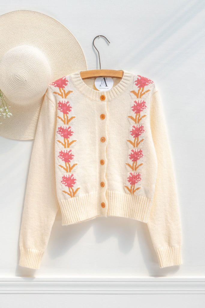 cottage core sweaters for autumn - a cream wooly cardigan with floral motives cottagecore style- on a hanger view 
