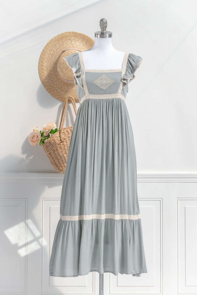 Elegant sage green cottagecore dress featuring lace trim and delicate embroidery, styled with a straw hat and a basket of roses, perfect for a quaint and charming look.