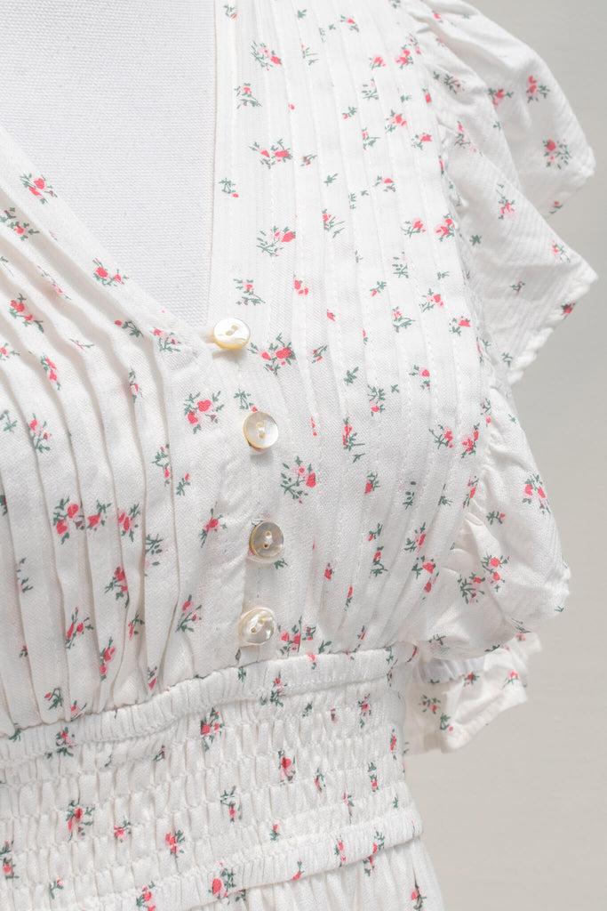 Parisian Parlour mini dress is the perfect addition to the dollette wardrobe. Featuring a lovely and delicate pink floral print on white cotton, short sleeves, a smocked elastic waistline, and pintuck-detailed skirt. aesthetic clothes - amantine - upclose fabric view 