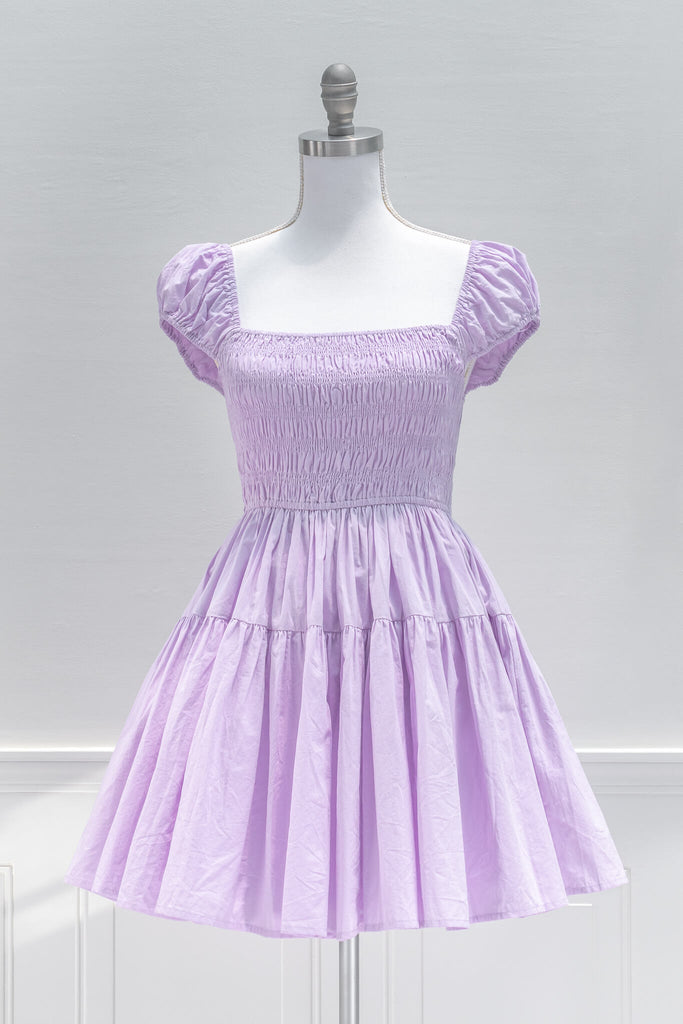 Sweet and feminine, the Lilac Meadows mini dress in lovely lavender cotton features a square neckline, short capped sleeves, fit-and-flare silhouette, and a smocked elastic bodice with side ties. Front View
