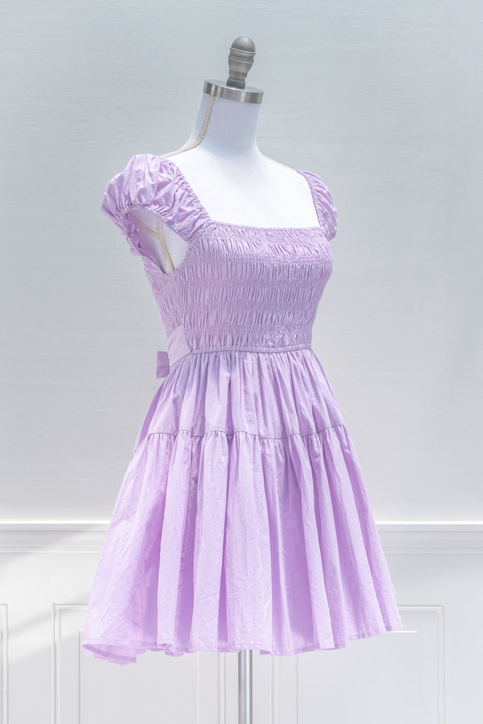 Sweet and feminine, the Lilac Meadows mini dress in lovely lavender cotton features a square neckline, short capped sleeves, fit-and-flare silhouette, and a smocked elastic bodice with side ties. quarter View