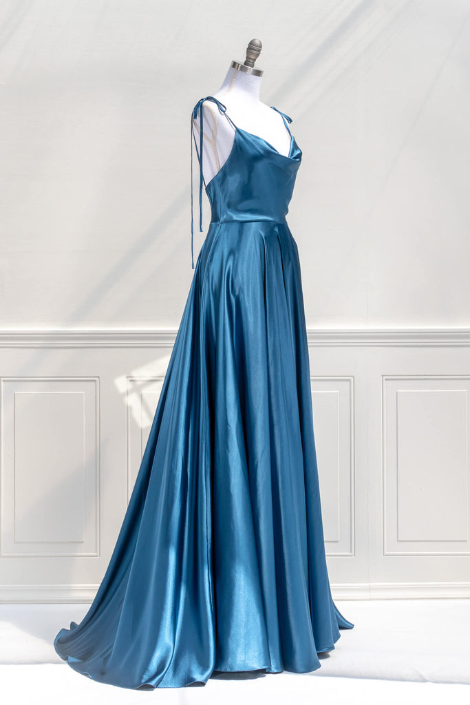 affordable formal gown for events. a long sapphire blue elegant formal dress with cowl neck and spaghetti straps. side view. Amantine. 