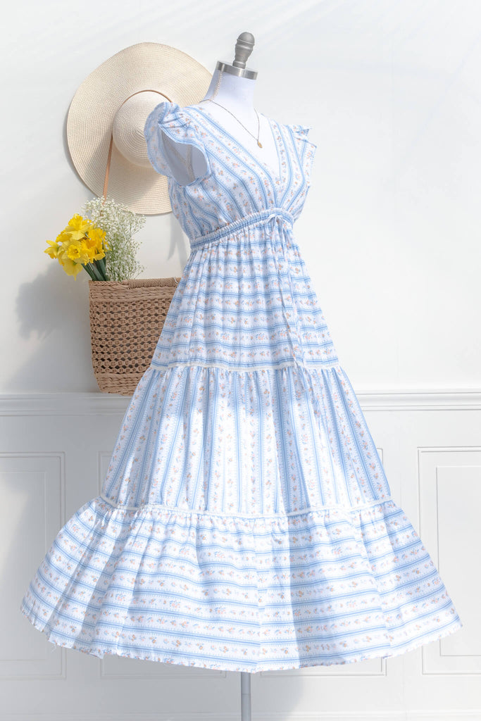 cottagecore dresses for spring. a french inspired dress with a v neck, ruffle sleeves, bow detail, and long skirt. made of a french country style print. quarter side view. amantine dresses.