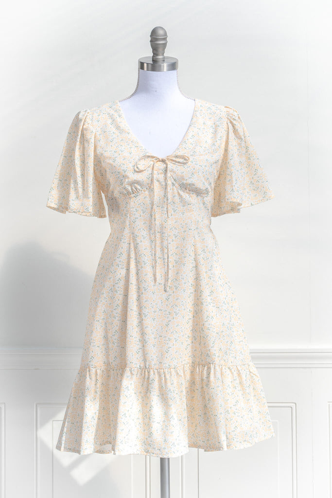 boutique dresses - a pretty mini dress with flutter sleeves, dresses with bows, and a v neckline. Yellow floral small print. cottagecore style. front view. 