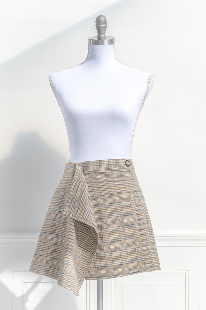 short skirts. a short skirt in light brown plaid. wrap around style. feminine short skirts. front unbottoned view. amantine.