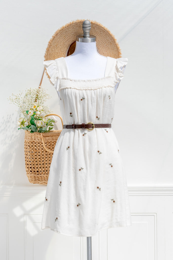 cottagecore dress - a sheath style chemise dress with small embroidered floral print on an off white flowy fabric. amantine cottage core dress. styled with a thin belt and french hat and bag.  view.