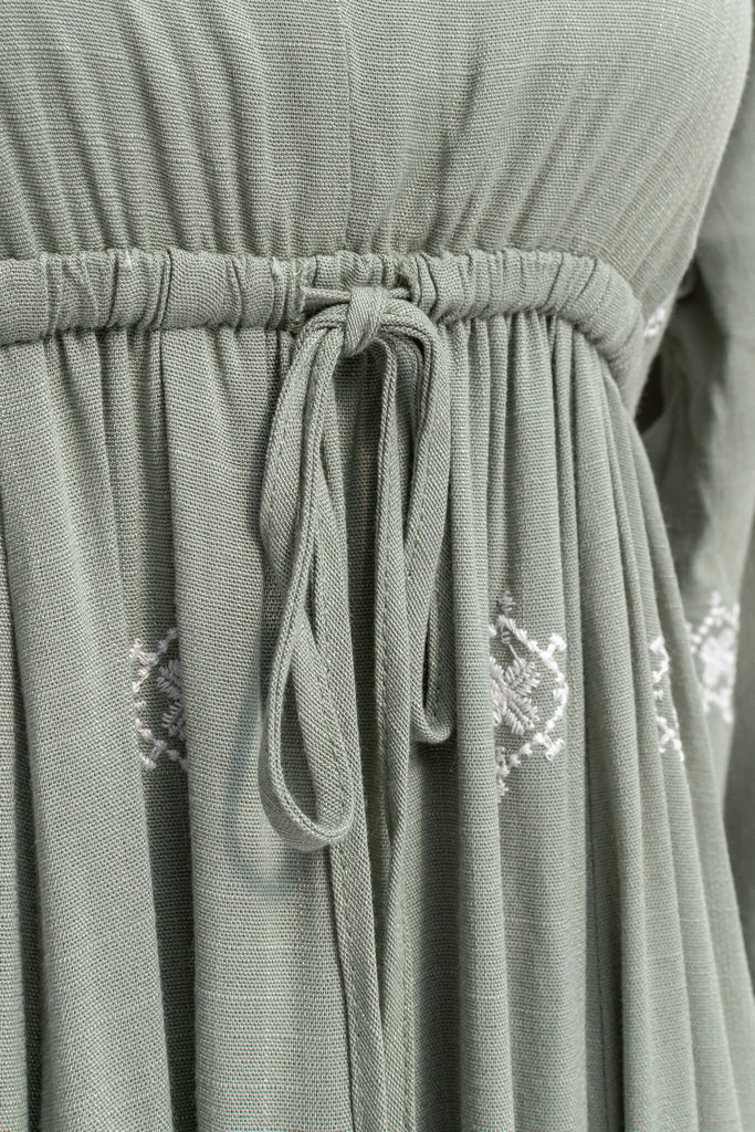 cottagecore dress - french style dress outfit for spring. v neck, tie waist, long sleeve, long skirt and beautiful embroidered hem. bow tie up close view. amantine. 
