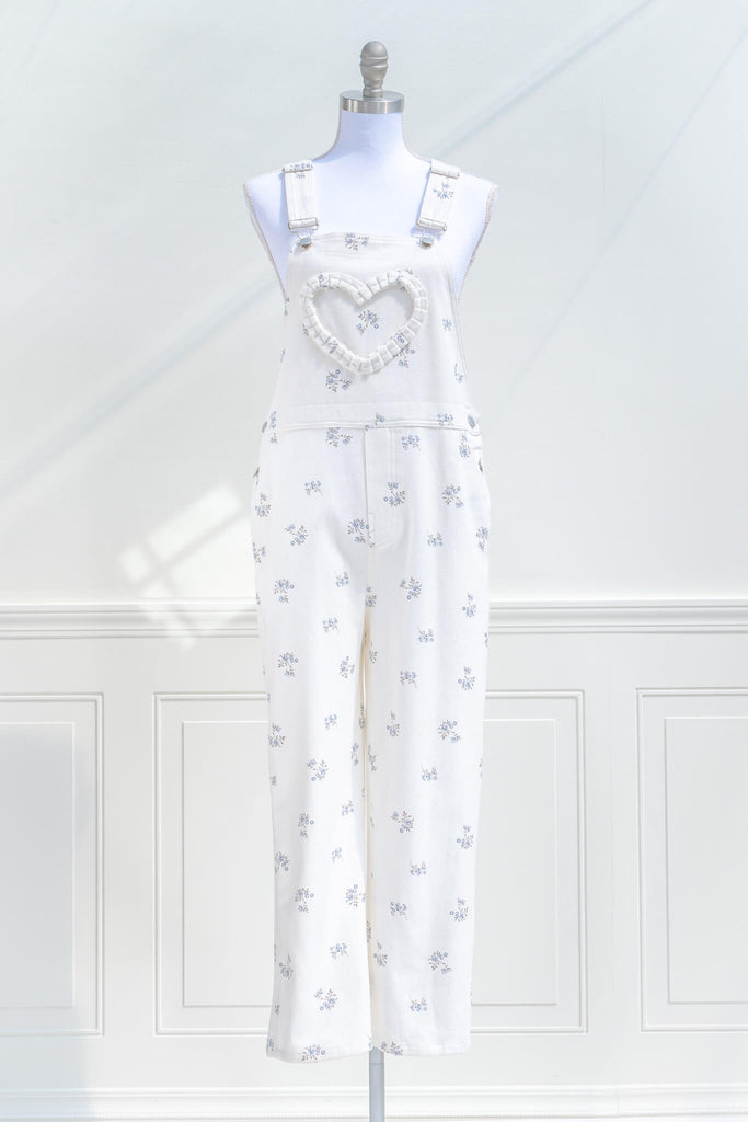 cottagecore outfits, a cottage core style jumpsuit, in white denim, small floral detail, and heart shaped applique detail. front view. amantine.