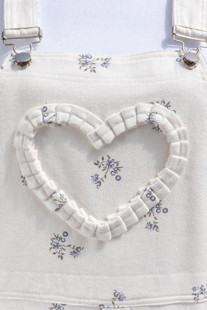 cottagecore outfits, a cottage core style jumpsuit, in white denim, small floral detail, and heart shaped applique detail. heart applique up close view. amantine.