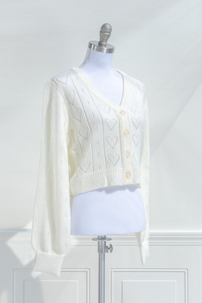 feminine tops - a french style cardigan sweater for spring. cream knit, button front, v neck, heart weave detail. side view. amantine. 