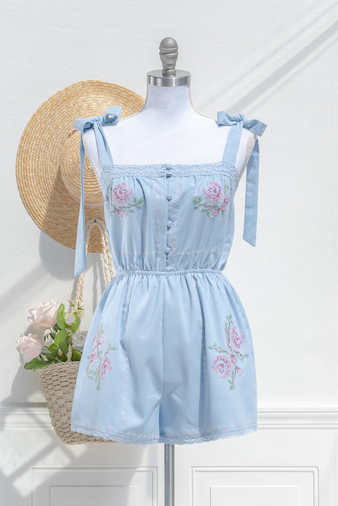cottagecore style romper in periwinkle blue for spring time. with floral embroidery details and lace. front view. amantine. 