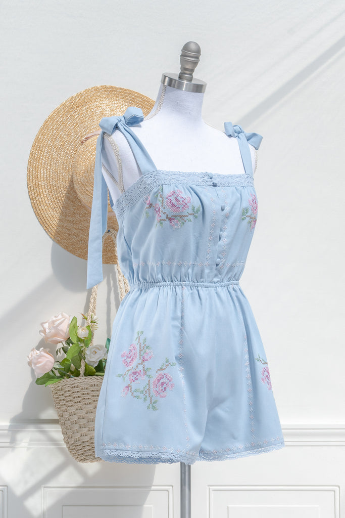 cottagecore style romper in periwinkle blue for spring time. with floral embroidery details and lace. 3/4 side view. amantine. 