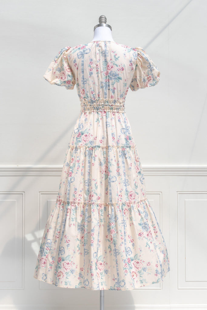 cottagecore dress - a beautiful v neck, puff sleeve, floral dress in feminine style. featuring blue and  mauve floral details on a beige fabric. back view. 