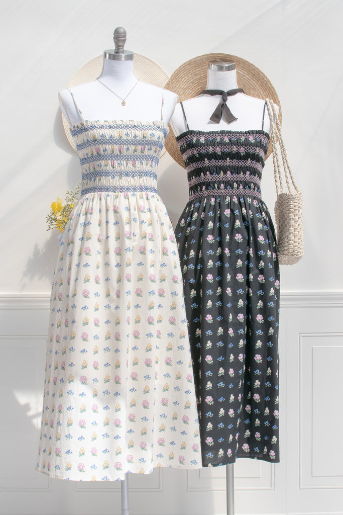 two cotton cottagecore dress - a black floral strap dress with ruched bodice, pockets, and an a line skirt. front view. 