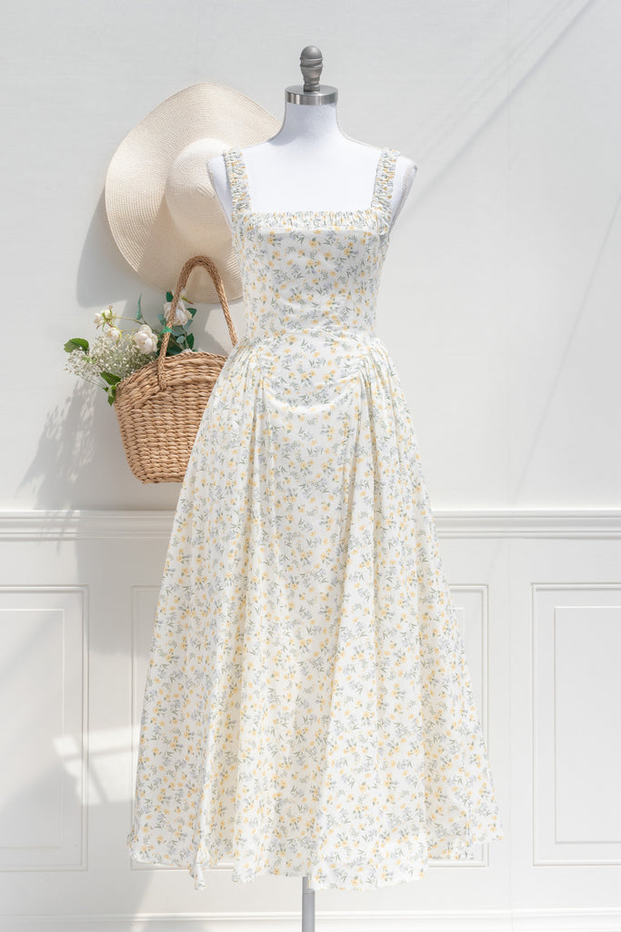 Front view of a romantic yellow floral cottagecore midi dress with a dropped waistline, ruched shoulder straps, square neckline, and tulle-accented hips for a Rococo-inspired silhouette.
