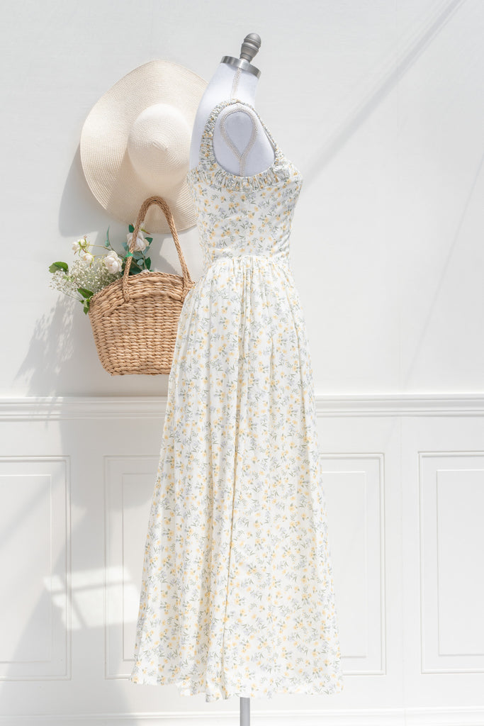 Side profile of a Rococo-inspired yellow floral midi dress, highlighting the dropped waist, romantic tulle detail at the hips, and soft ruching along the shoulders.