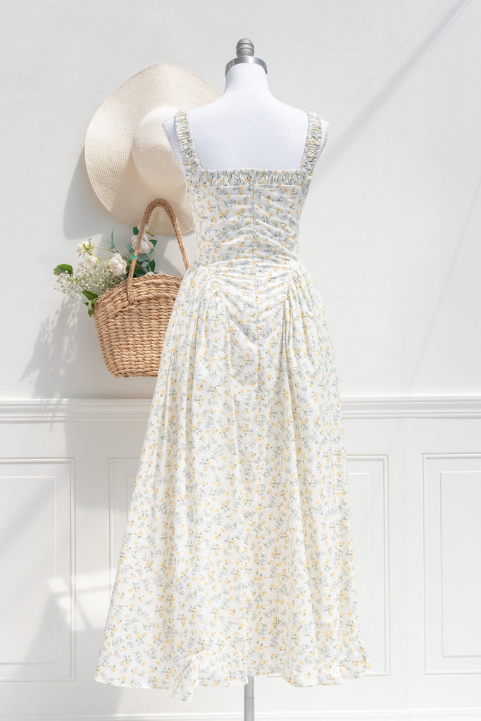 Back view of a vintage-style yellow floral dress featuring ruched straps, smocked back, and dropped waistline with tulle accents for a sculpted, romantic silhouette.