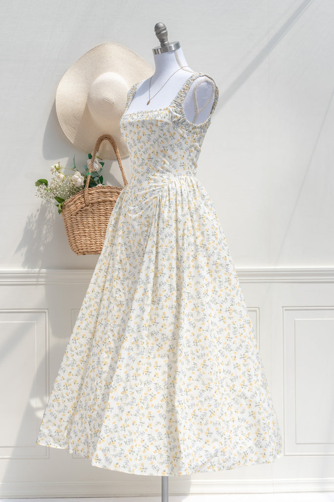 Three-quarter side view of Amantine’s Rococo-style floral midi dress, showcasing the delicate yellow print, ruched straps, and softly flared skirt with tulle-enhanced volume.