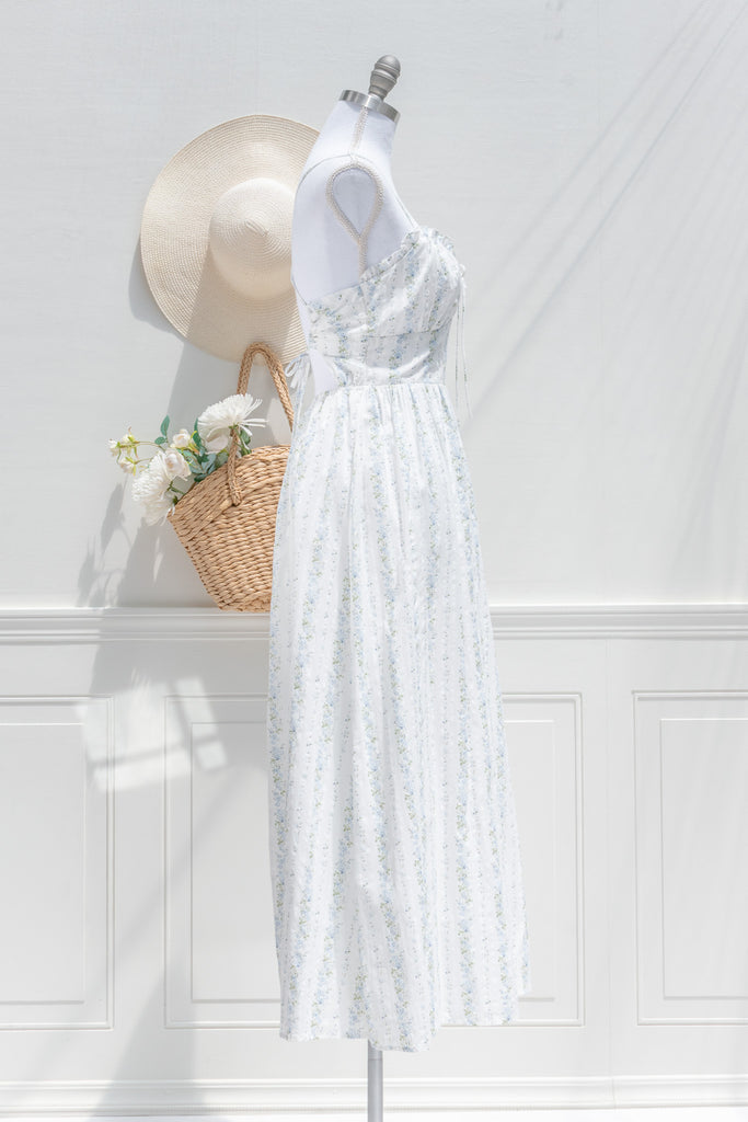 Floral cottagecore dress. Covered in soft vertical trails of blue and ivory florals, her silhouette feels like something from a countryside novel — soft, nostalgic, and effortlessly graceful. side view. Amantine french style.