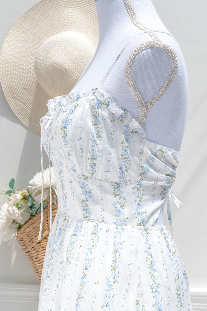 Floral cottagecore dress. Covered in soft vertical trails of blue and ivory florals, her silhouette feels like something from a countryside novel — soft, nostalgic, and effortlessly graceful. up close bust view. Amantine french style.