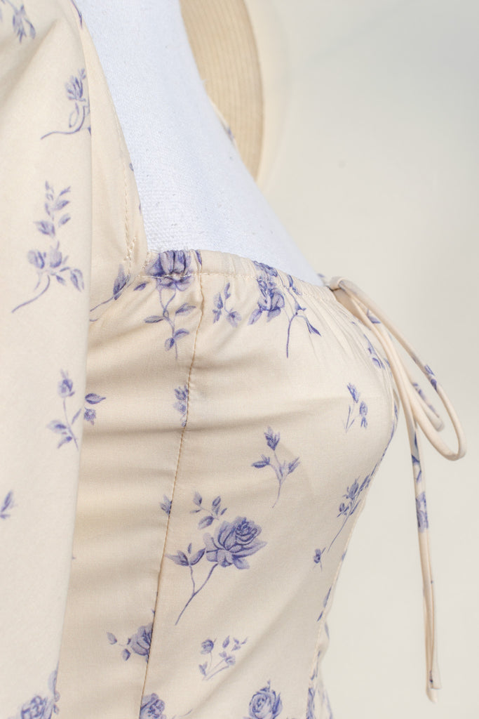 cottagecore dress - this dress is a flowing, romantic garment characterized by soft hues and delicate details that inspire feelings of nostalgia and whimsy. These dresses draw inspiration from the idyllic charm of life in a quaint, rural cottage from a bygone era as well as french country cottage charm. up close view of floral detail. 