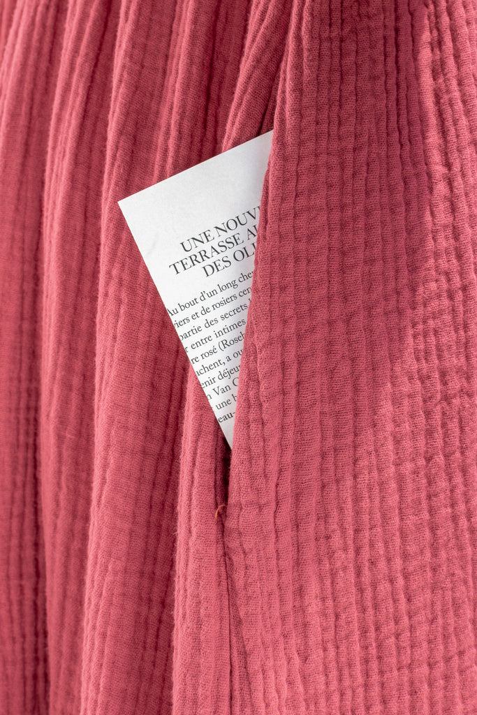 Close-up of a textured pink fabric with a white card partially visible.
