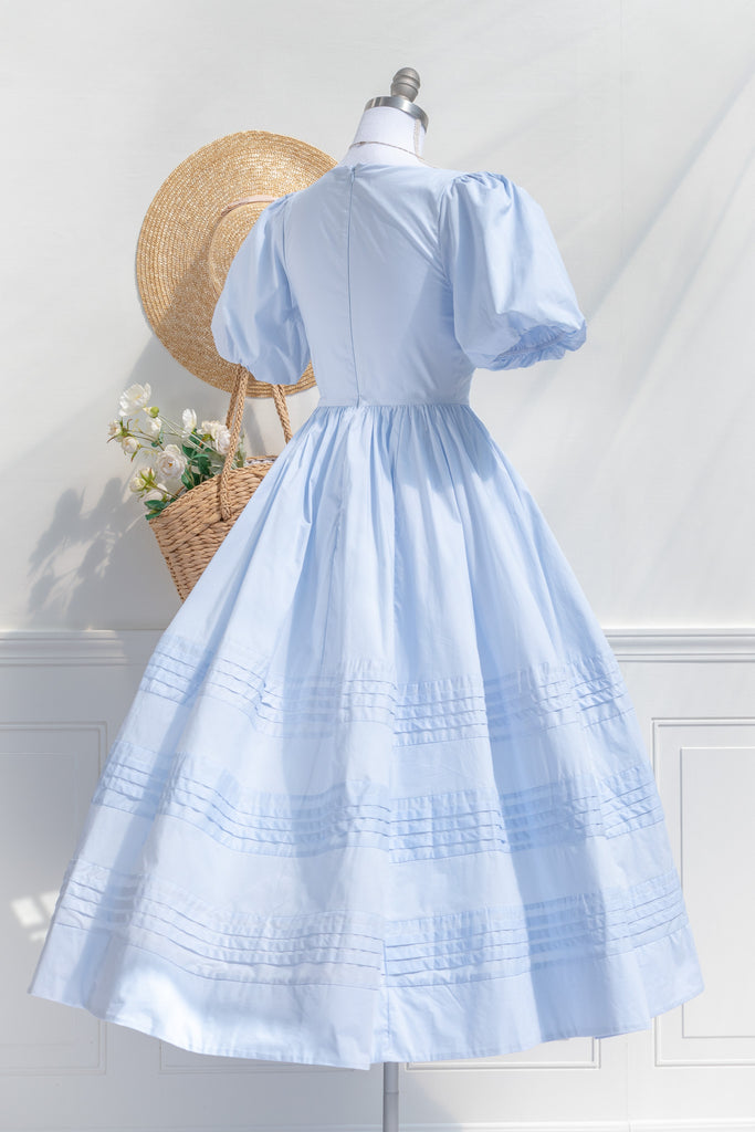blue cottagecore dress - soft cotton dress with round neckline, puff sleeves, side pockets, and a long a line skirt. perfect for brunches in springtime. back side view. 