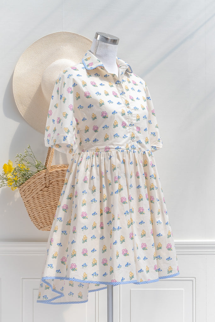 a pretty spring time midi dress - button down short sleeve floral mini dress. with pretty colorful floral details, blue trim, and in cottagecore style. 3/4 side view. 