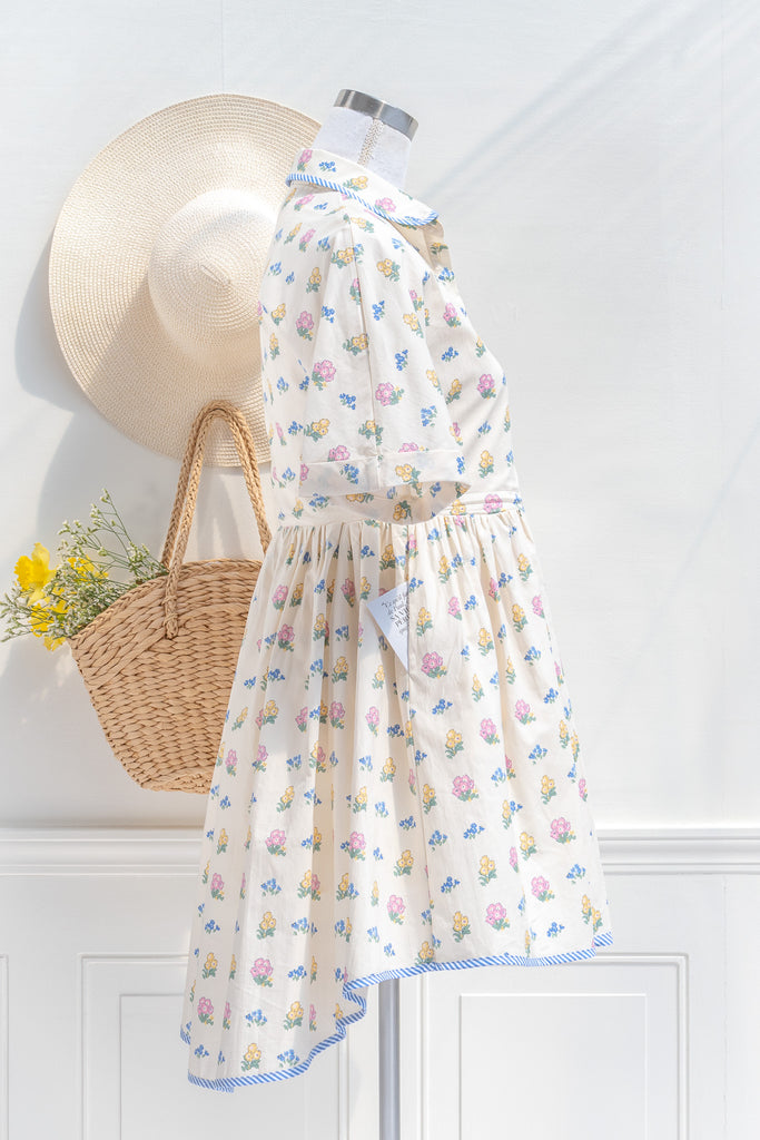 a pretty spring time midi dress - button down short sleeve floral mini dress. with pretty colorful floral details, blue trim, and in cottagecore style. side view. 