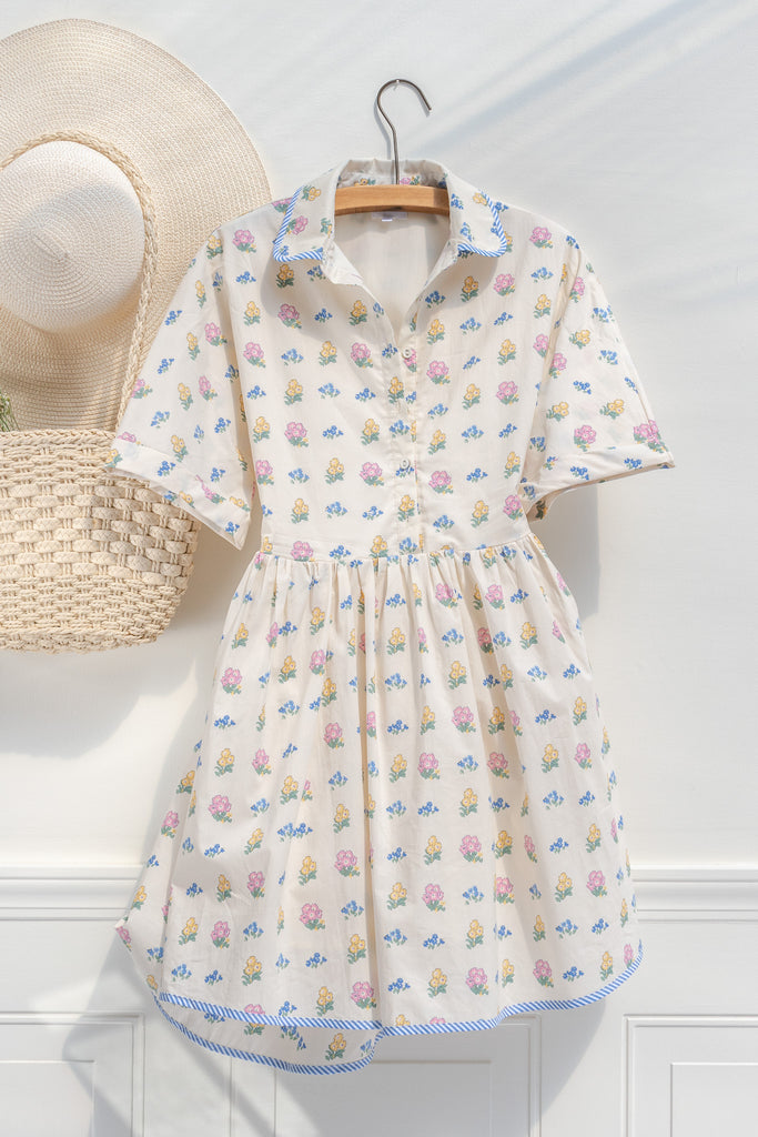a pretty spring time midi dress - button down short sleeve floral mini dress. with pretty colorful floral details, blue trim, and in cottagecore style. hanger view. 