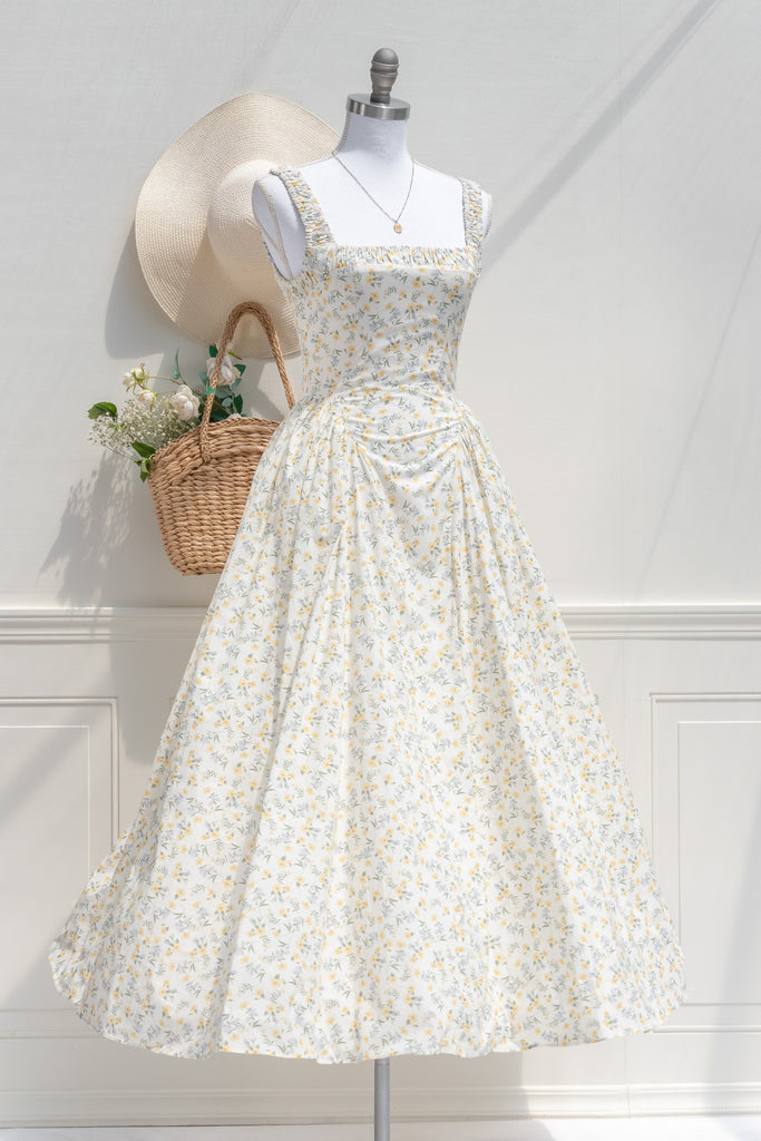 Three-quarter side view of Amantine’s Rococo-style floral midi dress, showcasing the delicate yellow print, ruched straps, and softly flared skirt with tulle-enhanced volume.