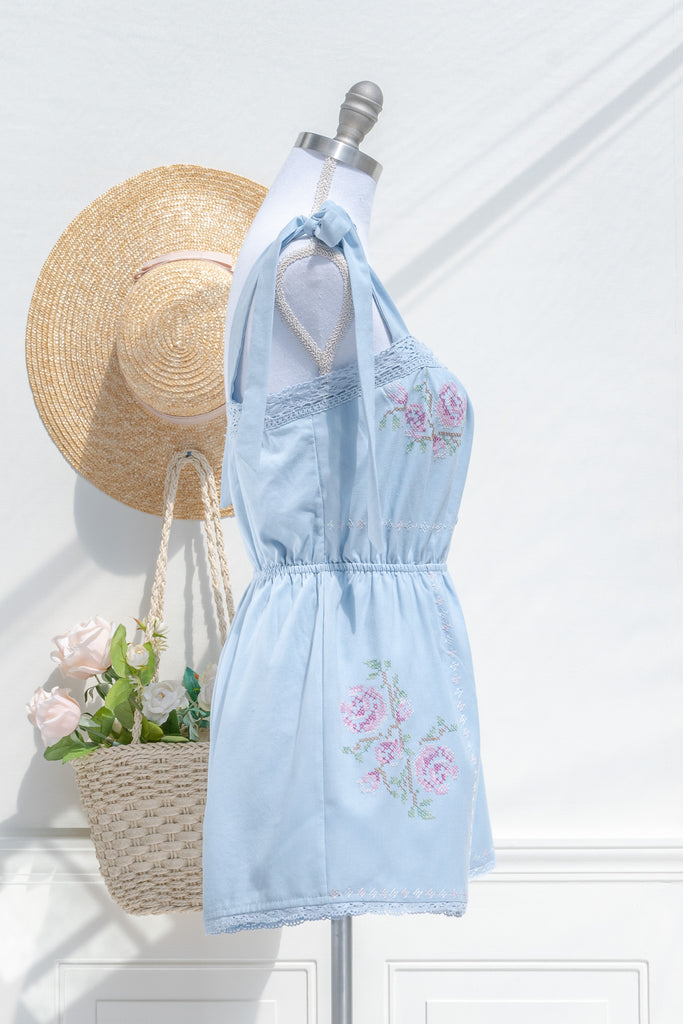 cottagecore style romper in periwinkle blue for spring time. with floral embroidery details and lace. side view. amantine. 