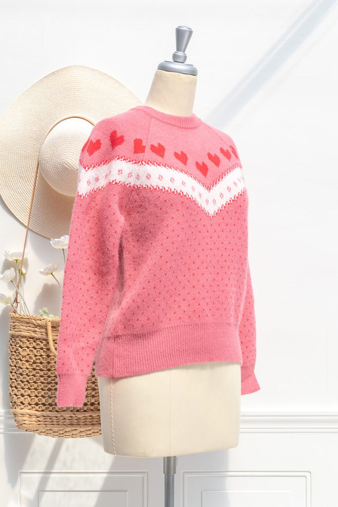 cute sweater in pink, with heart details and crew neck. strawberry color. side view. 