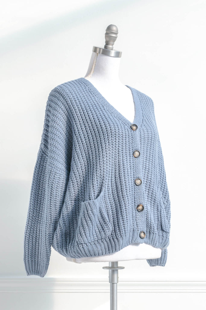 cute winter cardigan in a feminine and vintage style cut. cardigan with pockets and button down details. blue knit. side view. amantine. 
