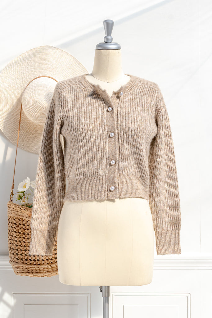 A cozy and comfy cardigan for autumn, the Isobel sweater features faux-pearl buttons, cropped length, a crew neckline, and long sleeves in a soft taupe knit. front view. 