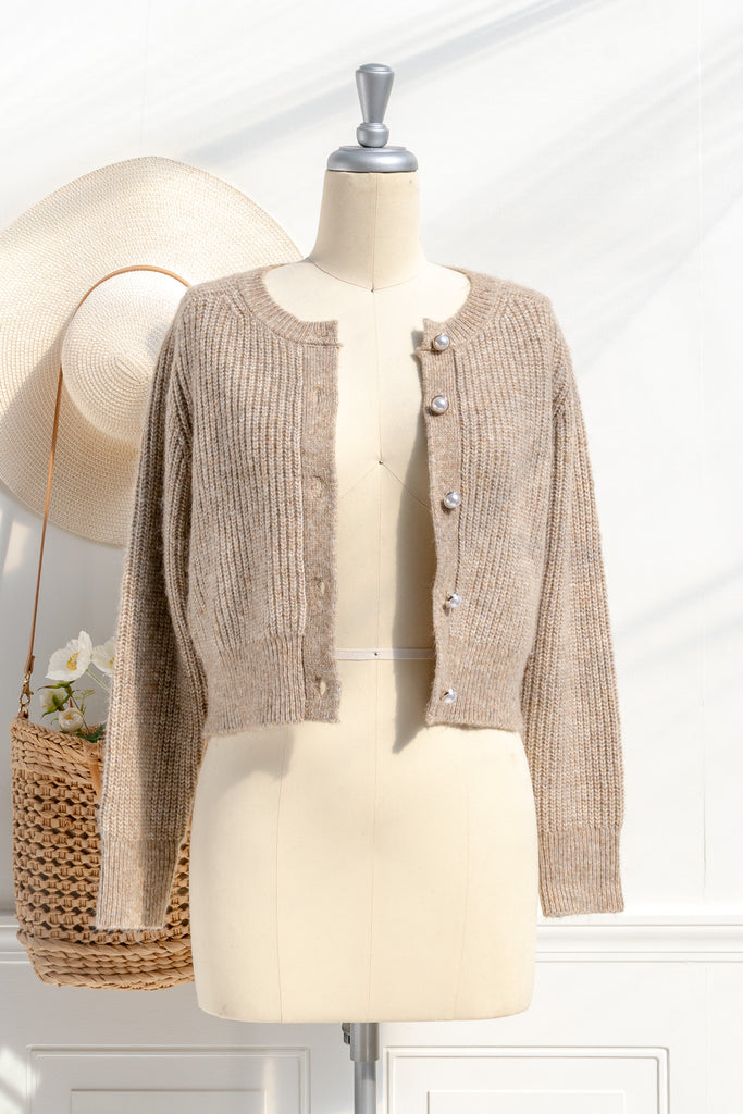 A cozy and comfy cardigan for autumn, the Isobel sweater features faux-pearl buttons, cropped length, a crew neckline, and long sleeves in a soft taupe knit. front view. 