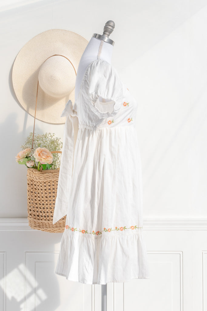 side view of white cottagecore dress with puff sleeves orange floral embroidery and a flowing skirt offering an effortless and feminine silhouette.