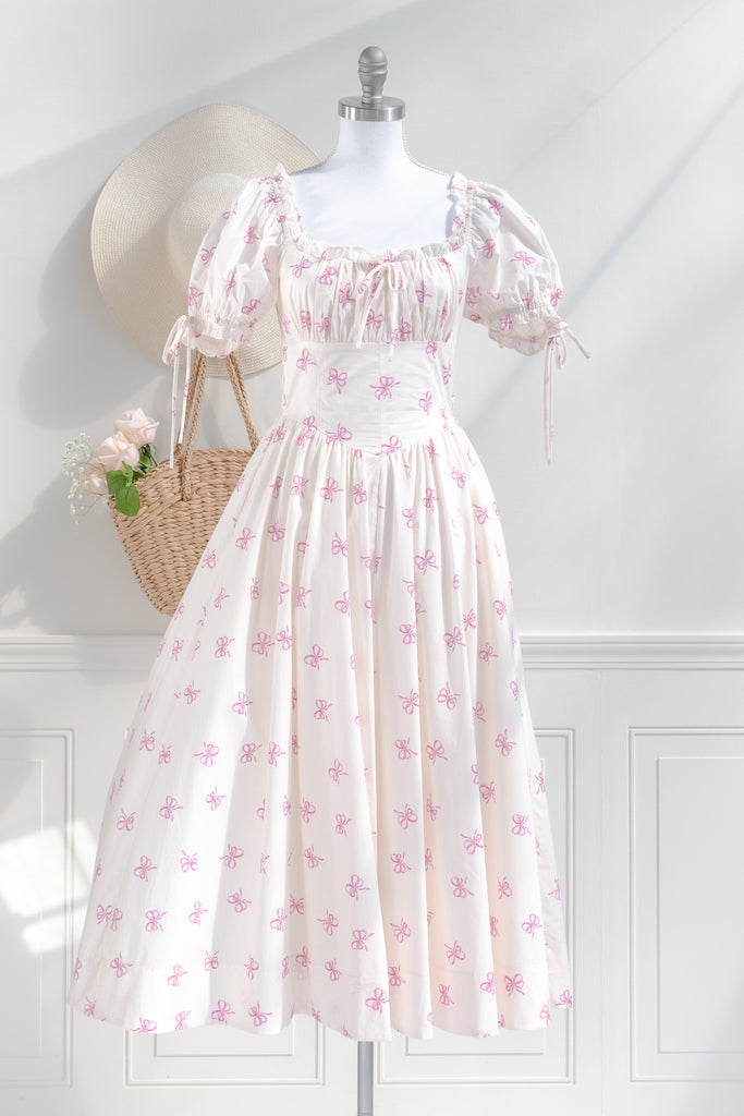 a cottagecore style dress with a very feminine style. it has puff sleeves, ruched bust, and a beautiful pink bow print. Front view. 