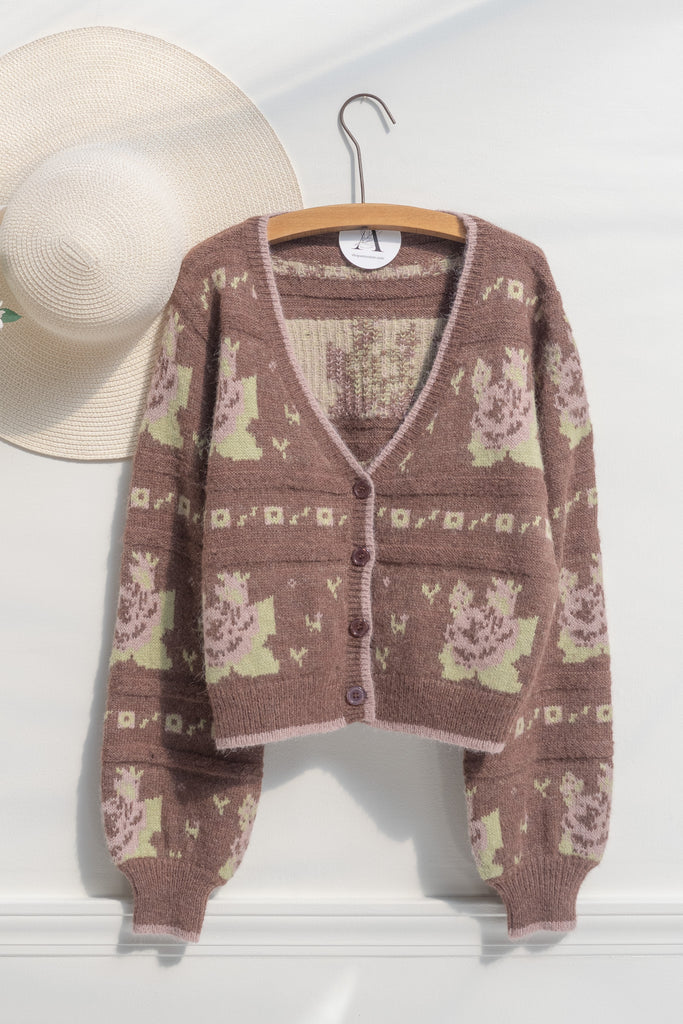 cute sweaters for fall. a floral abstract print light brown and green button down cardigan. hanger view. 