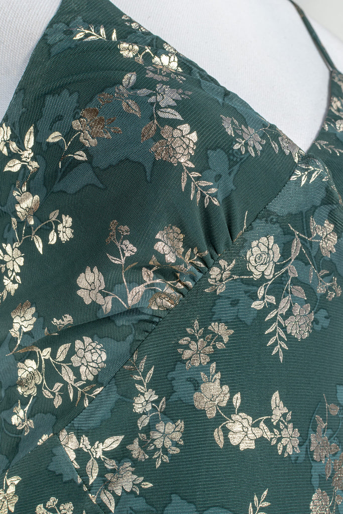 French dresses - inspired by feminine, elegant, cottagecore styles. A green dress with gold metallic floral detail. amantine dresses. up close fabric view. 