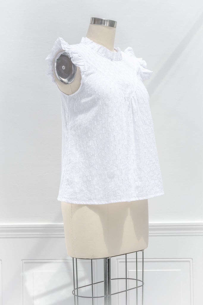 feminine tops - a cottagecore style white blouse with a ruffled crew neckline, ruffled sleeves, and white fabric. quarter side view. 