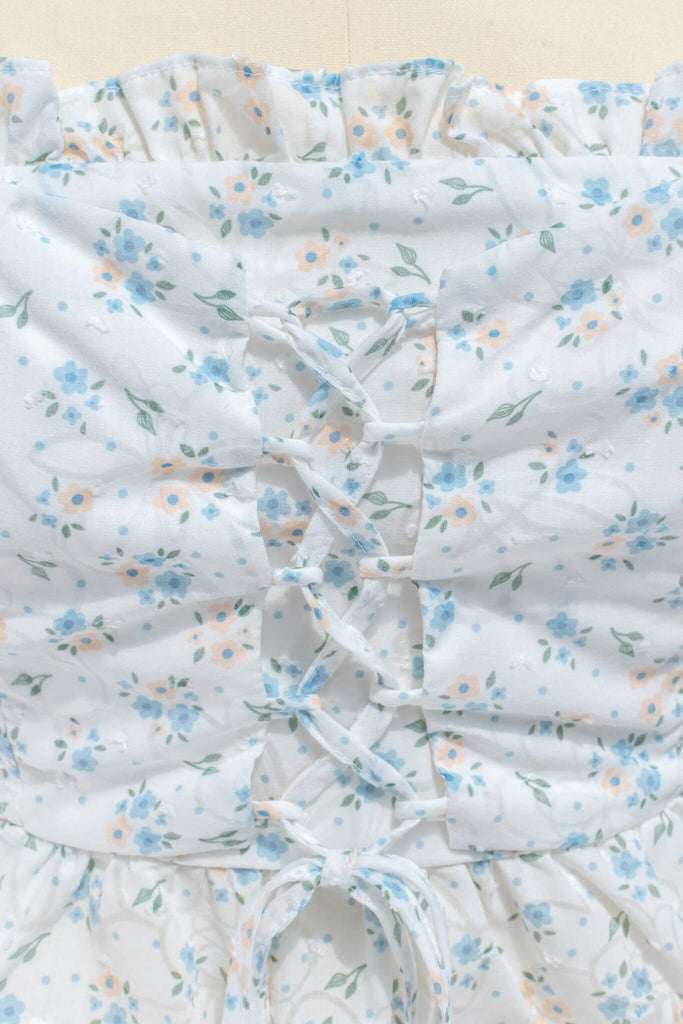 up close photo of fabric showing small blue, green, and light orange floral details. 