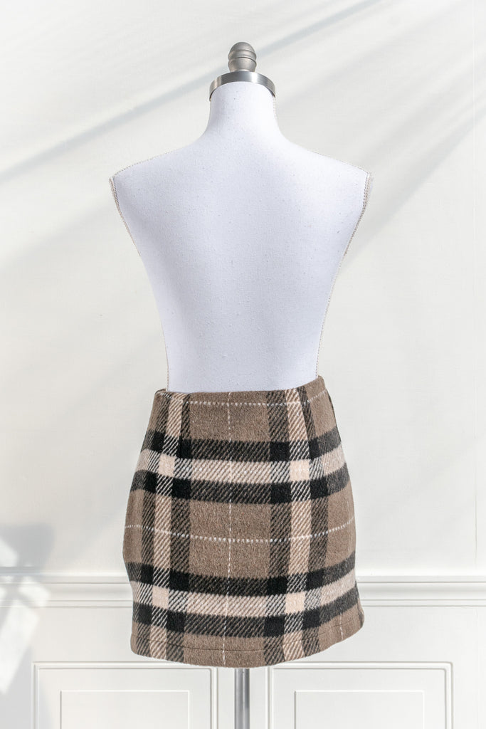 feminine clothing. a mini skirt features a soft tartan plaid print and a short length. Perfect with tights, a cardigan, and beret for a French-inspired collegiate look. back view. 