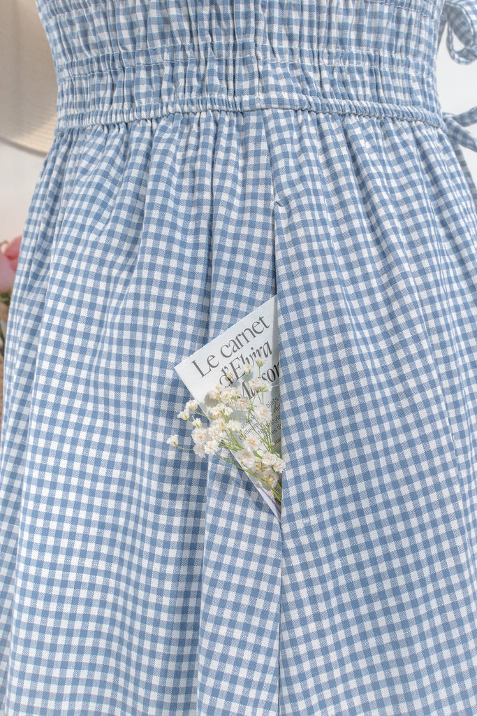 feminine and french inspired blue gingham dress. with ruffled straps, three bows, and pockets. perfect for cottagecore and french girl style ootd for spring. amantine. view of side seam pocket. 