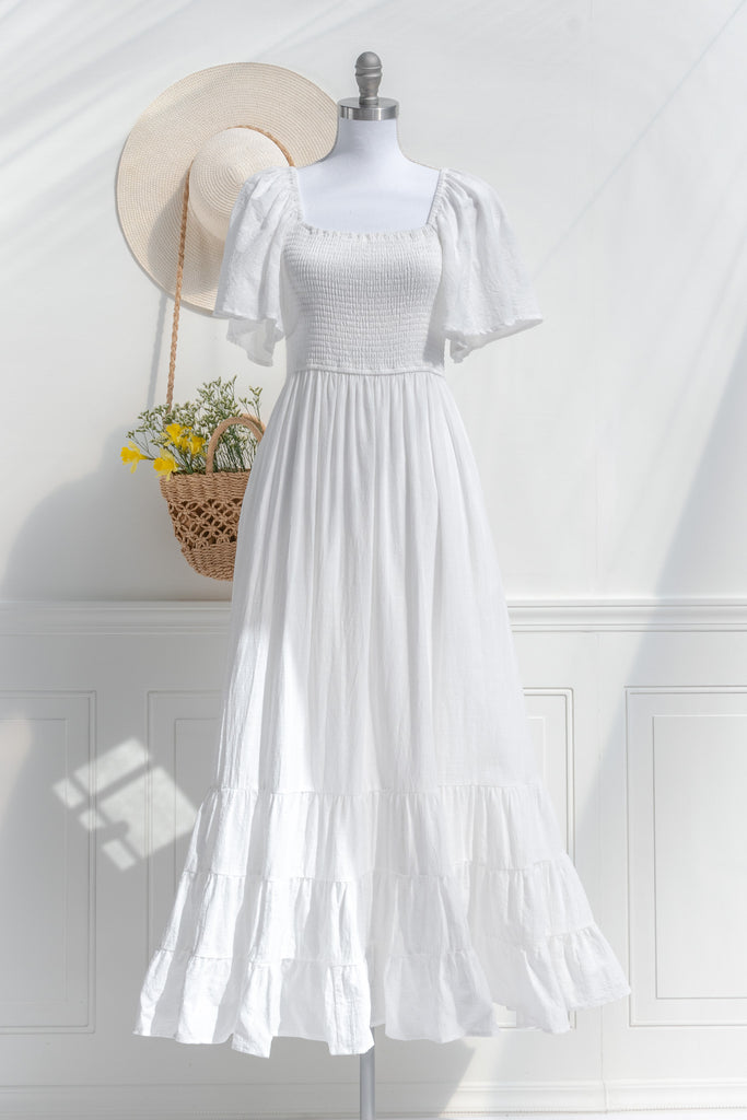 feminine clothing - a long white dress in a french and cottagecore style. featuring soft cotton fabric, bell sleeves, square neckline, and pockets. perfect for spring ootd. front view. 