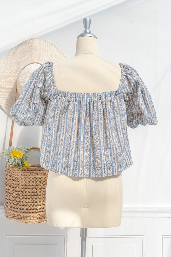 feminine tops - a cute feminine blouse in blue and gray floral detail. cotton, square neckline, puff sleeves. back view. 