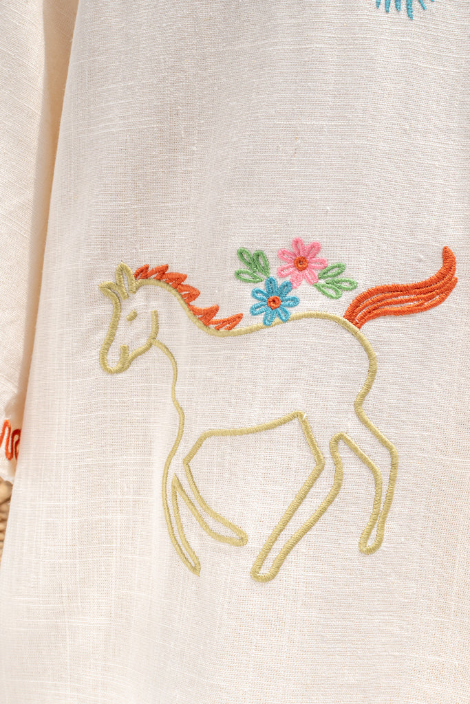 feminine clothing - a very unique summer set featuring a short sleeve button down shirt and shorts. In cream linen blend, it features very cute embroidery including a horse, and florals. A beautiful choice for your summer getaways. up close view of horse embroidery detail view. amantine french style clothing. 
